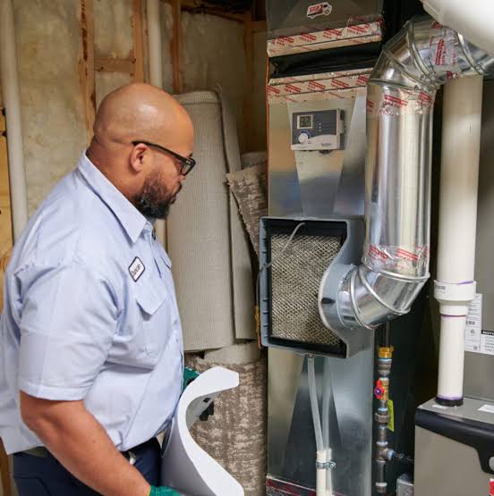 Technician inspecting a furnace air filter and connected ductwork